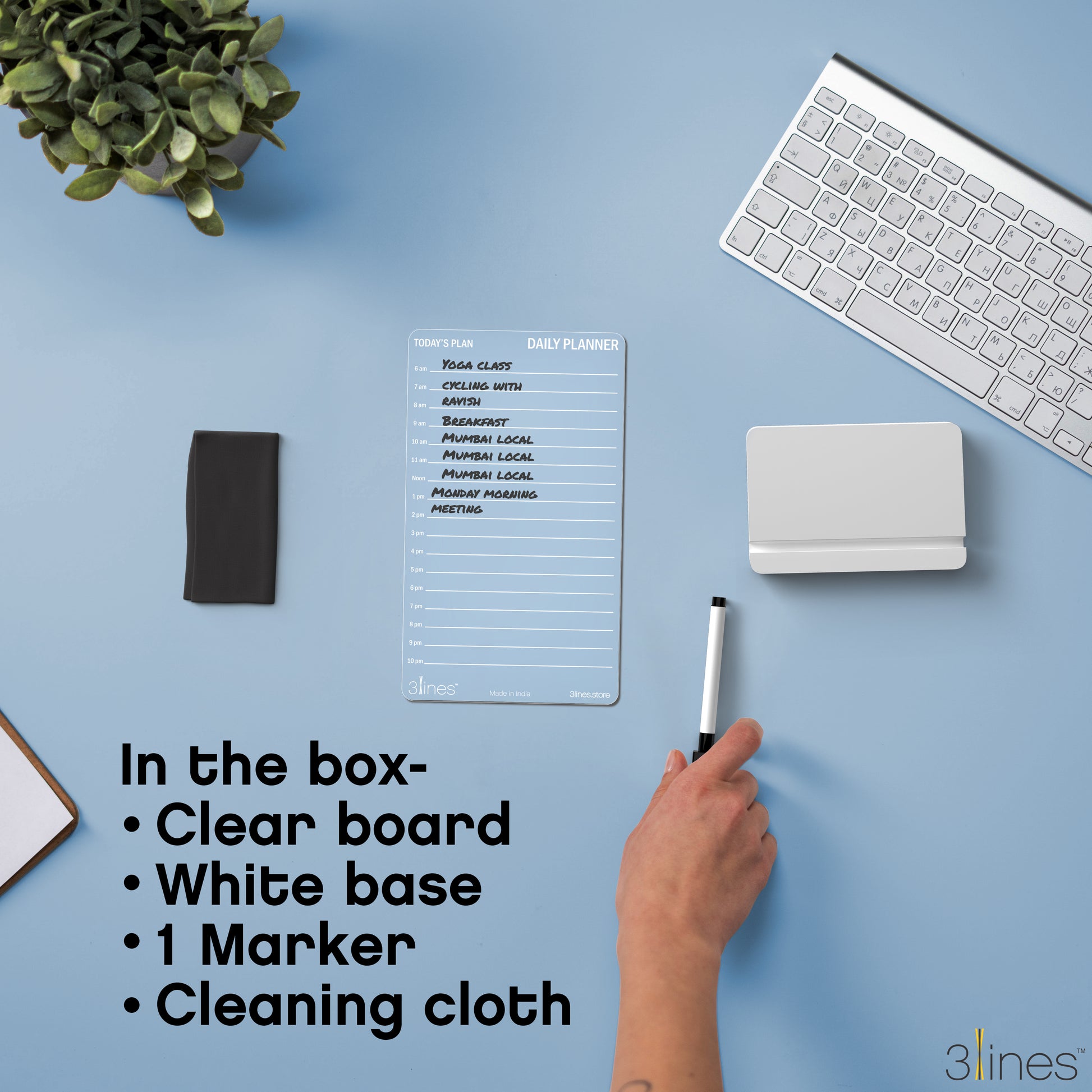 Clear planner board with marker on a blue desk with keyboard and plant